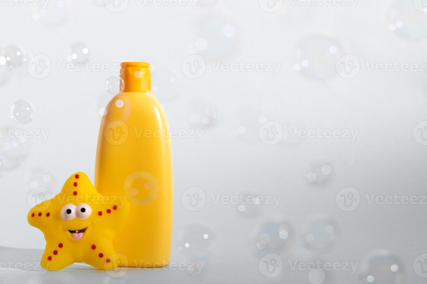 Baby bath foam or liquid soap with yellow star fish and many flying soap bubbles on white background. Children's bath time concept. Copy space. photo