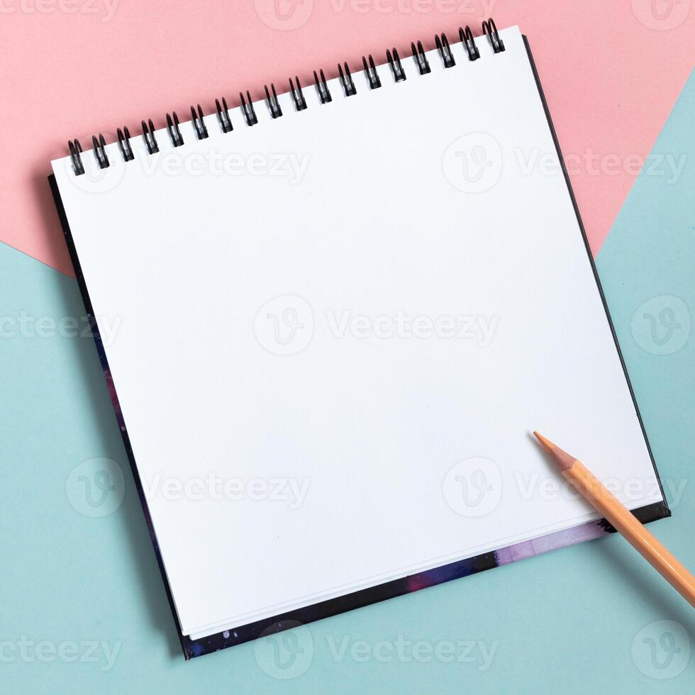 Mock-up of empty spiral sketchbook on pastel pink and blue background. Top view of open notebook with clean sheet. Template for message. Copy space. photo