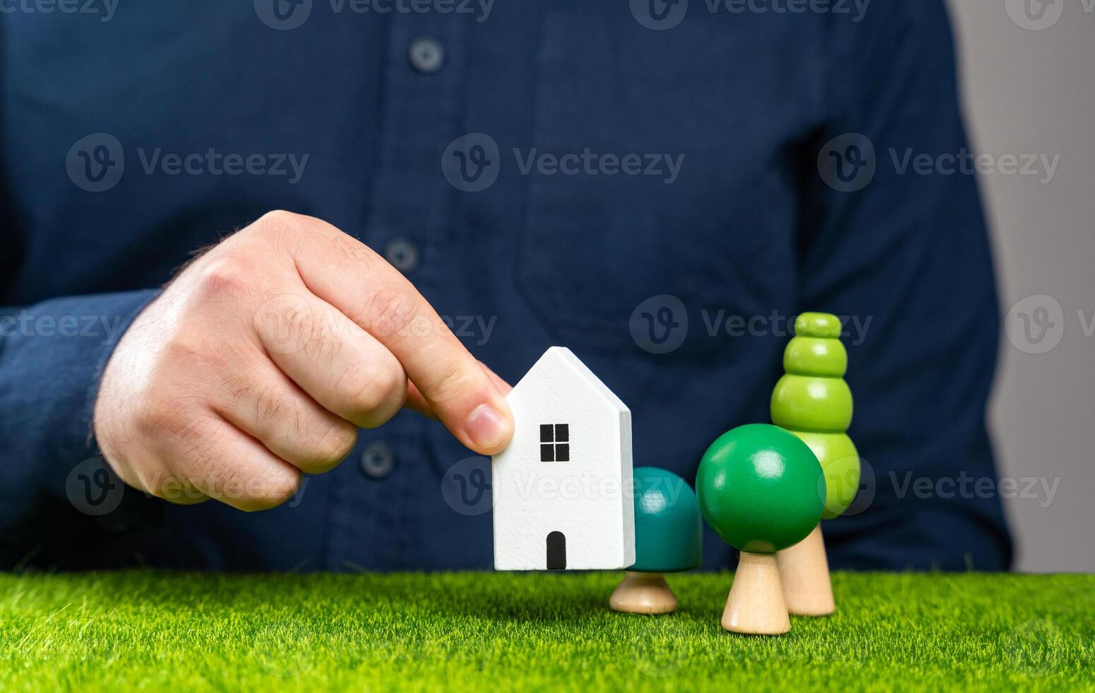 A man places a house figurine on a plot of land. Build a new house on the plot. Develop or use the land for residential purposes. Buying a property. photo