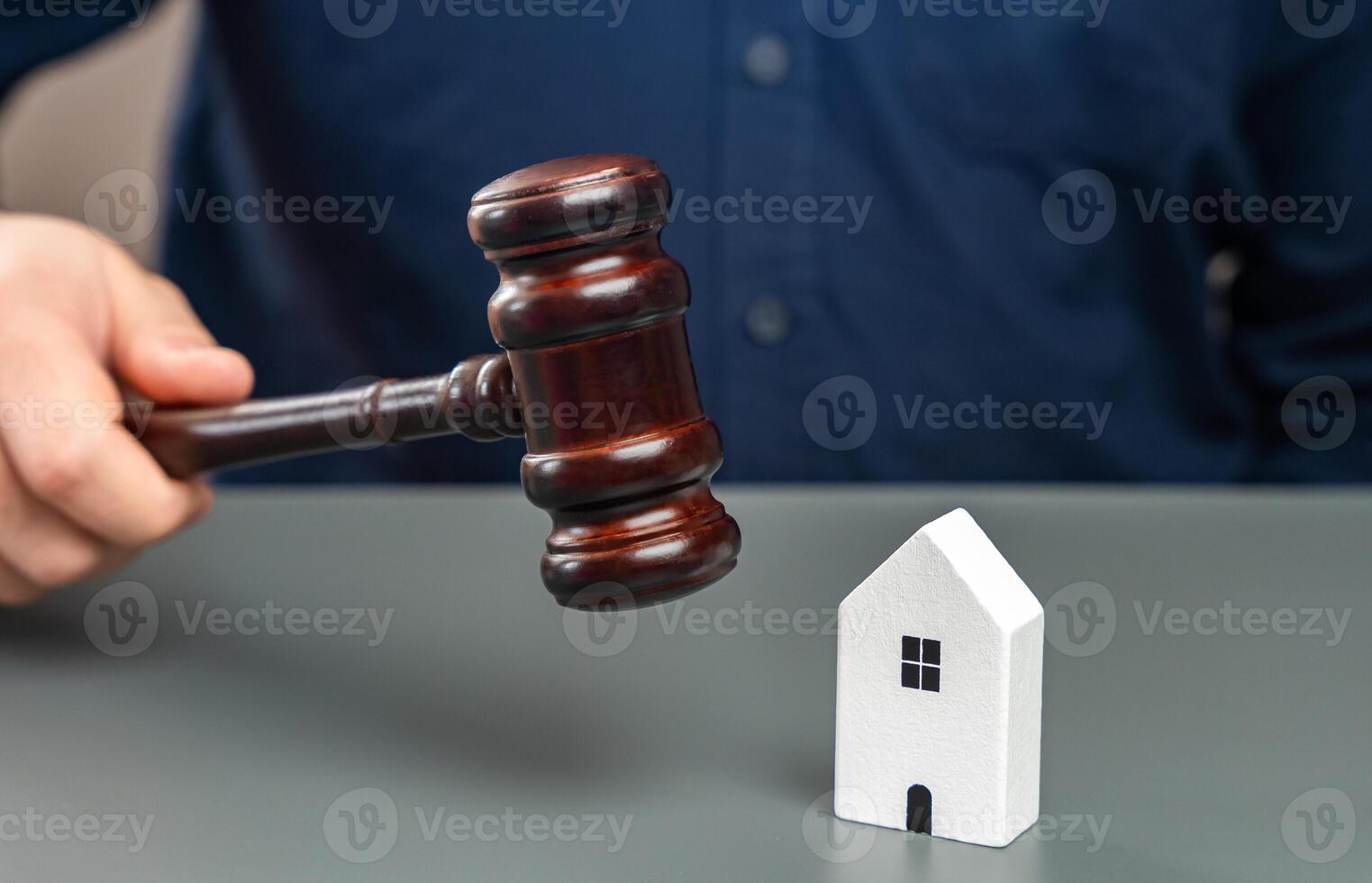 A figurine of a house and a man with a judges gavel. Real estate court decisions. Property inheritance litigation. Establishment of ownership. Amnesty for violations of construction rules. photo