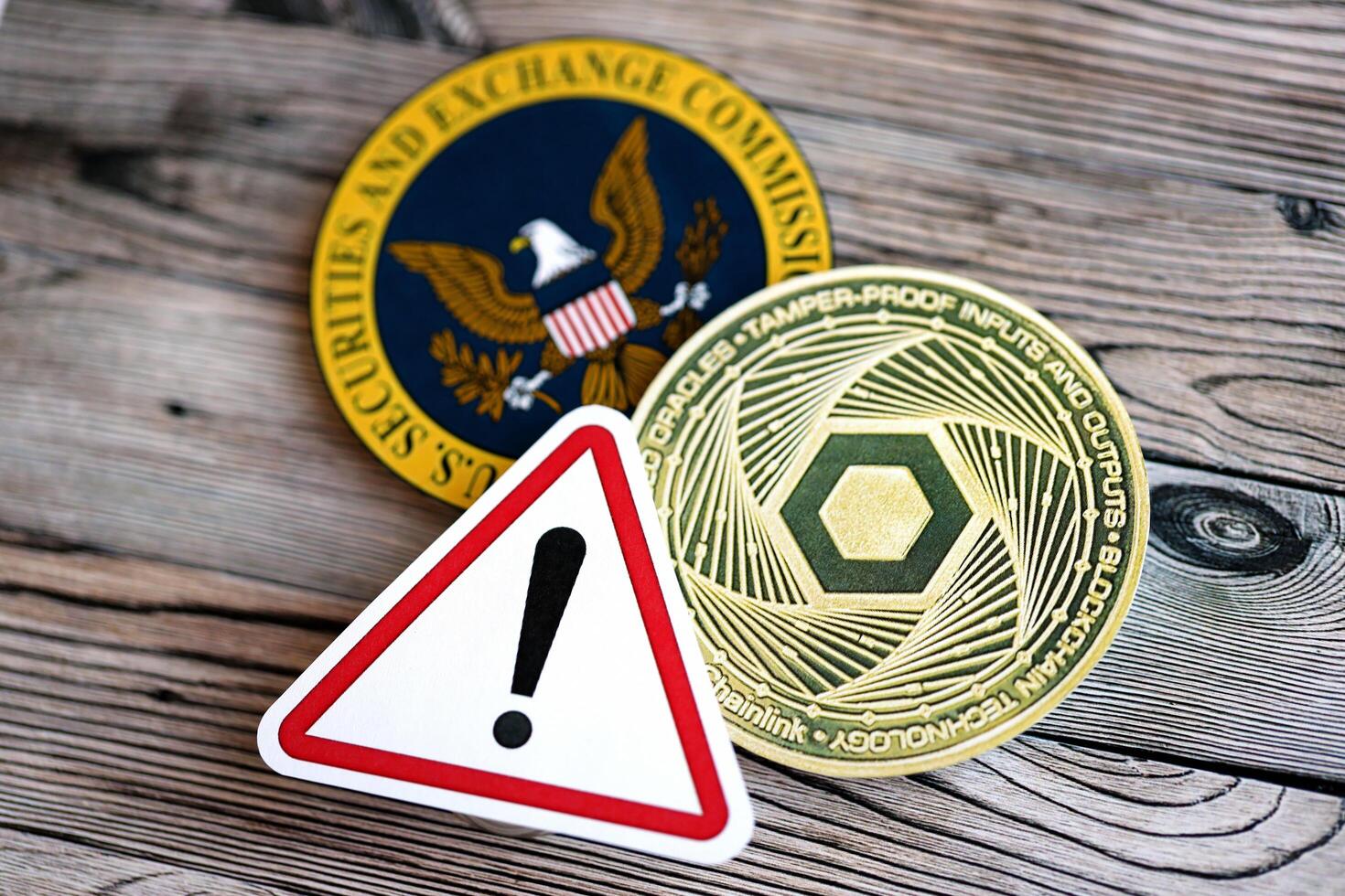 KYIV, UKRAINE - AUGUST 17, 2024 Chainlink LINK coin and red paper attention sign with Securities and Exchange Commission on wooden background photo