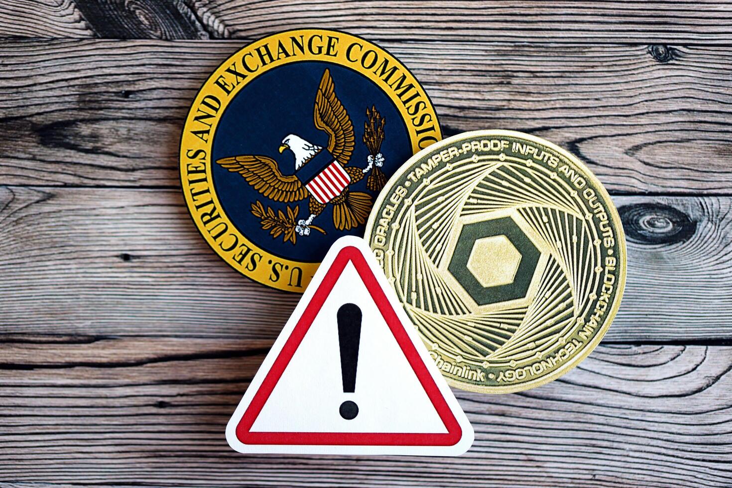 KYIV, UKRAINE - AUGUST 17, 2024 Chainlink LINK coin and red paper attention sign with Securities and Exchange Commission on wooden background photo