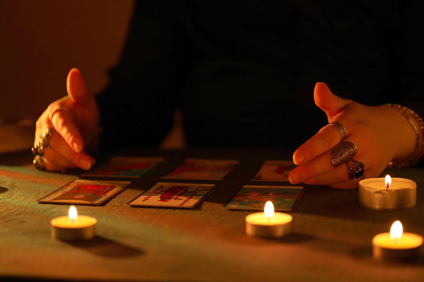 KYIV, UKRAINE - JULY 10, 2024 Tarot reader picking tarot cards. Candlelight in dark room. Tarot reader or fortune teller reading and forecasting photo