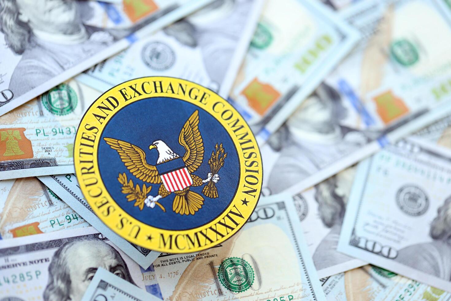 KYIV, UKRAINE - JUNE 26, 2024 U.S. Securities and Exchange Commission coat of arms on big amount of US dollar banknotes photo