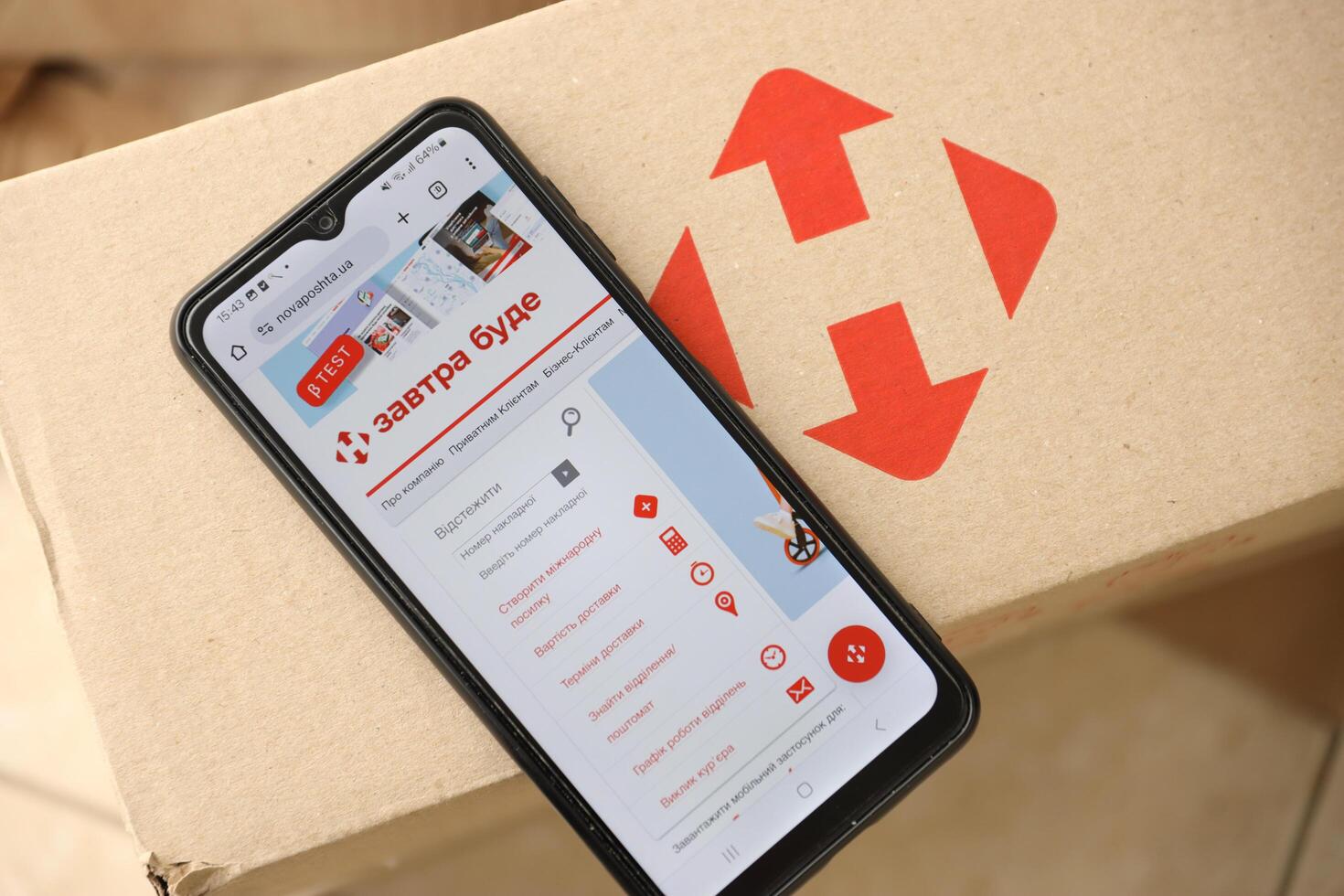 KYIV, UKRAINE - APRIL 20, 2024 Nova Poshta Logotype on cardboard box and website on smartphone screen. Nova Poshta is best ukrainian postal service company photo