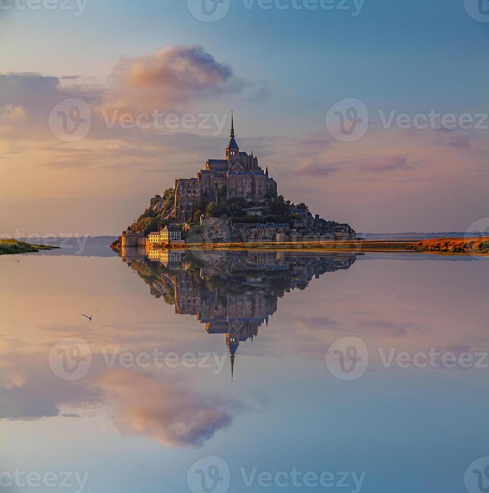 Panoramic view of the famous Le Mont Saint-Michel abbey reflected in high tide at sunset photo