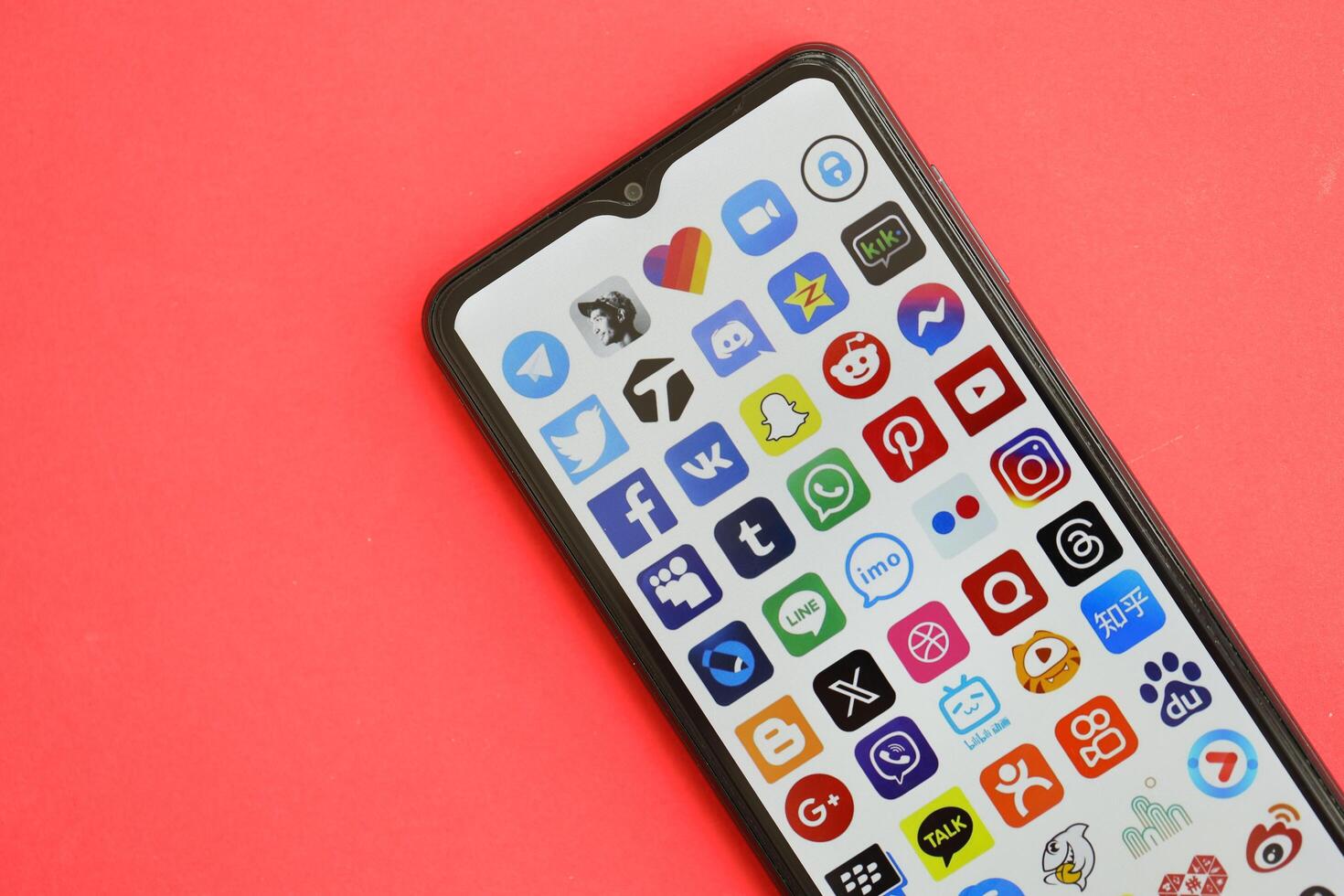 KYIV, UKRAINE - APRIL 1, 2024 Many apps icon on smartphone screen on red table photo