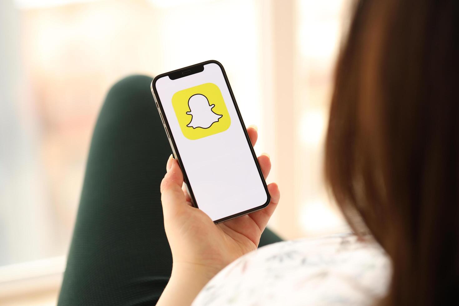 KYIV, UKRAINE - APRIL 1, 2024 Snapchat icon on smartphone screen in young female hands photo