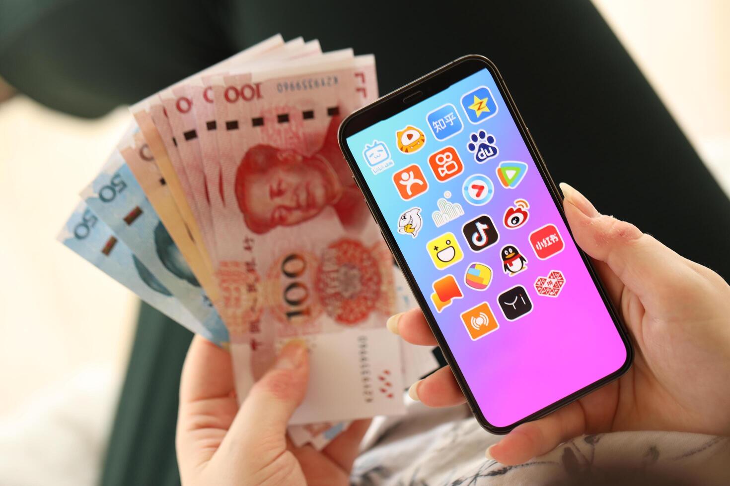 KYIV, UKRAINE - APRIL 1, 2024 Asian apps icon on smartphone screen and money in female hand photo