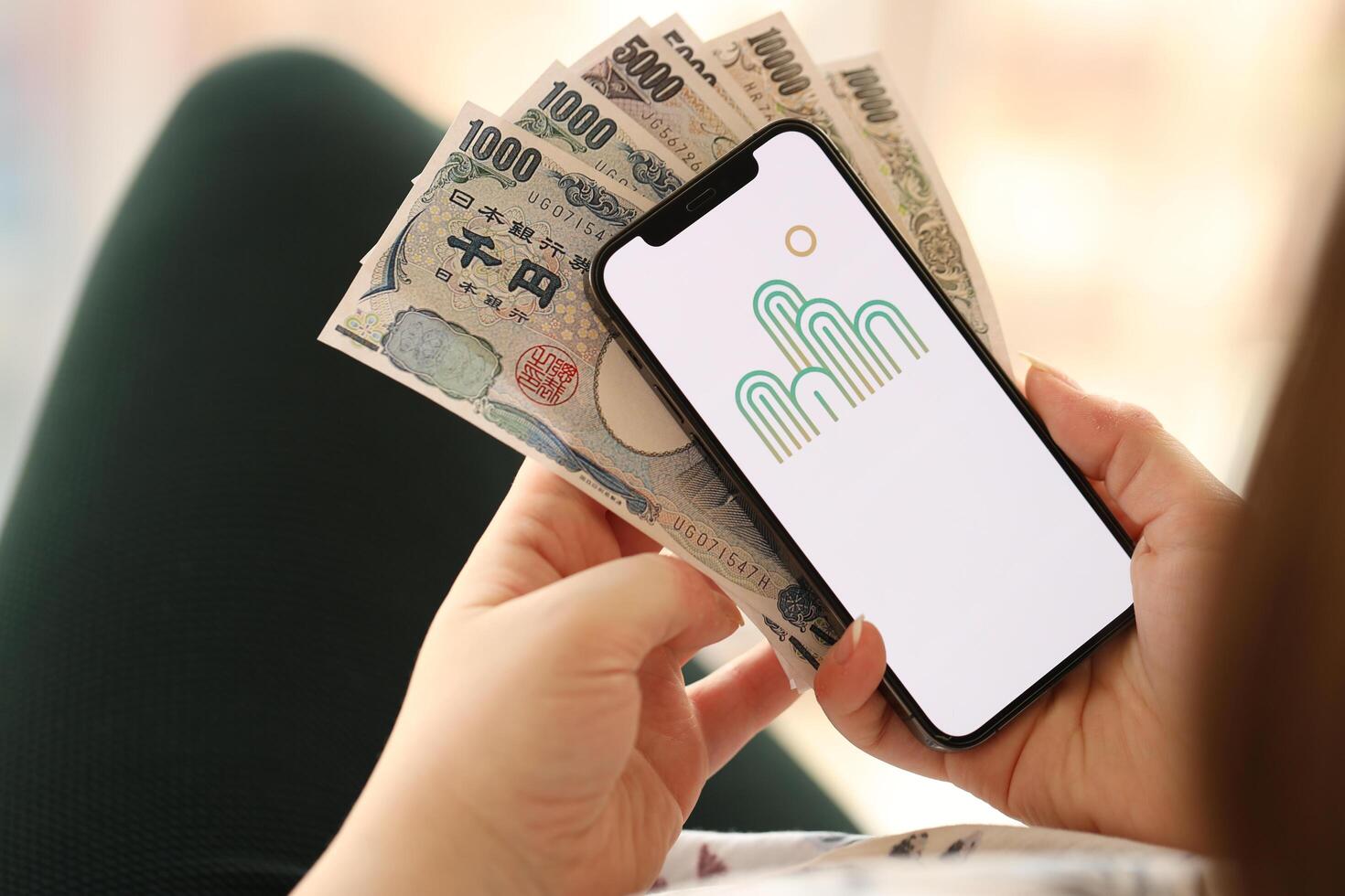 KYIV, UKRAINE - APRIL 1, 2024 Oasis icon on smartphone screen and money in female hand photo