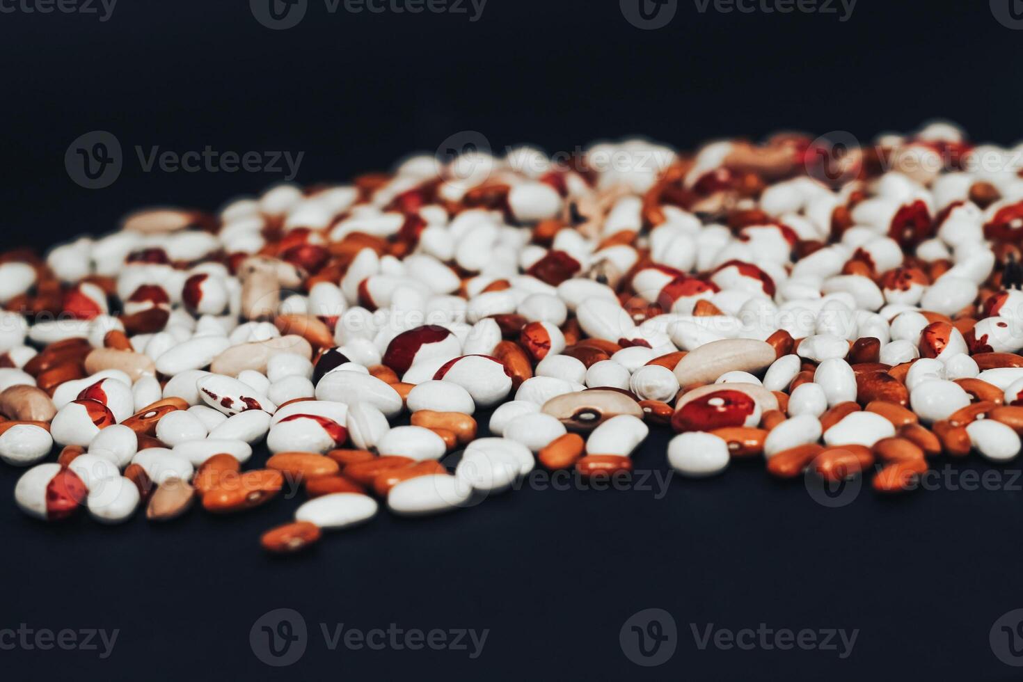 View from above. multi-colored beans scattered on a black background. background with space for text photo