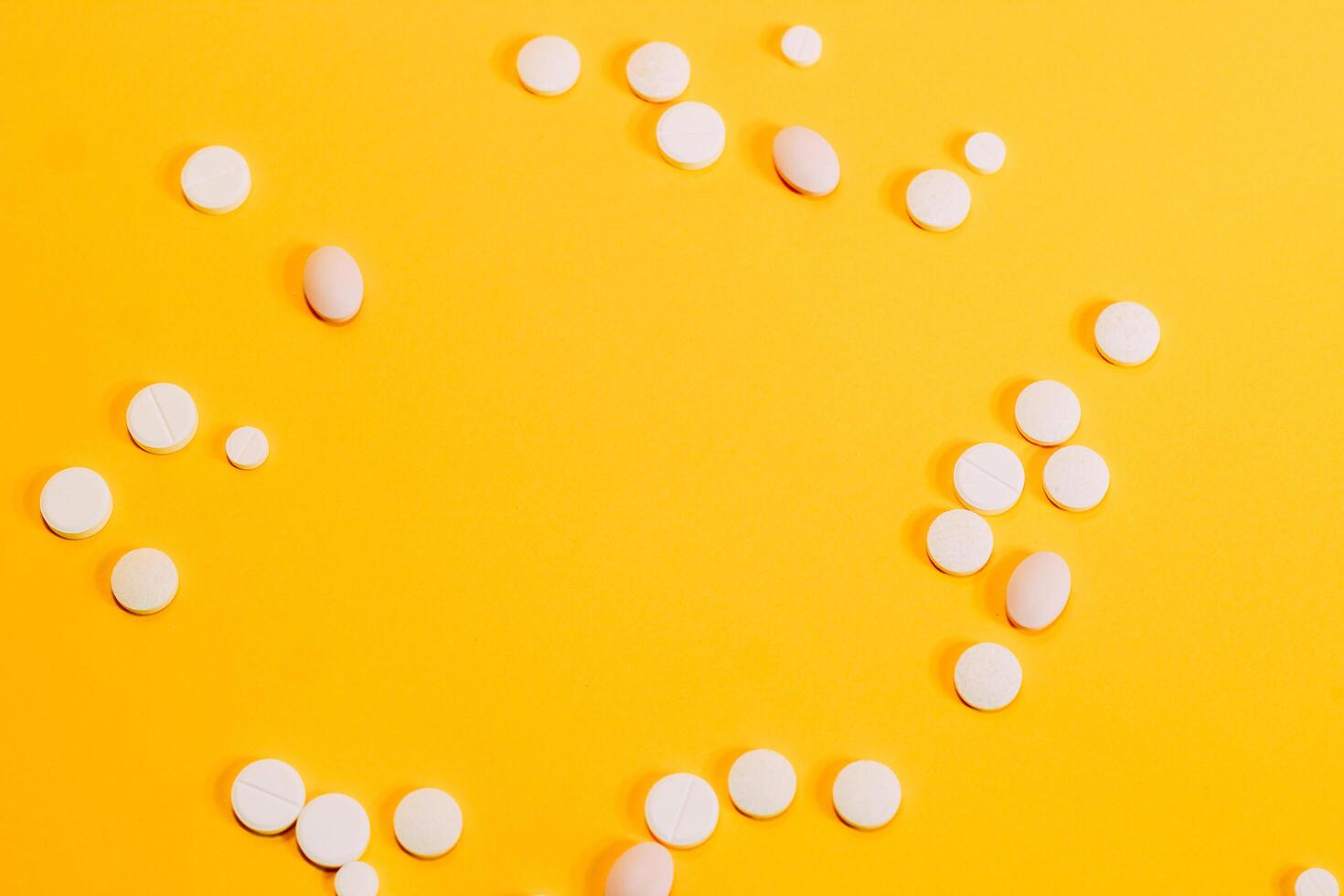 Different pills and vitamins are scattered on a yellow background. space for text photo