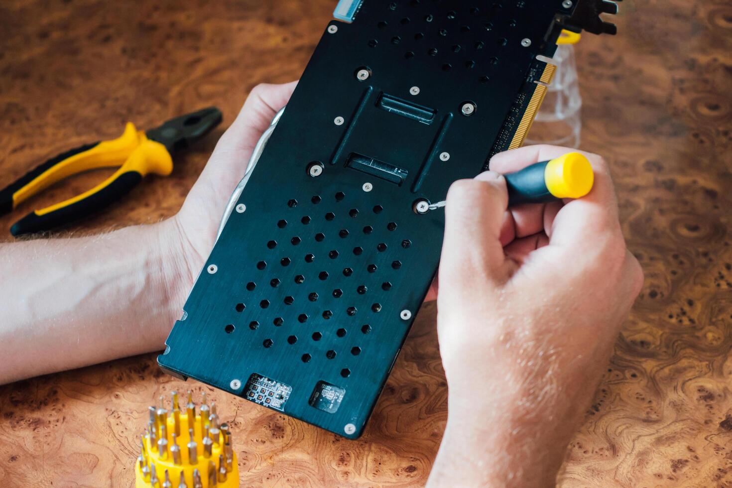 Male hands hold a screwdriver and repair computer graphics card. photo