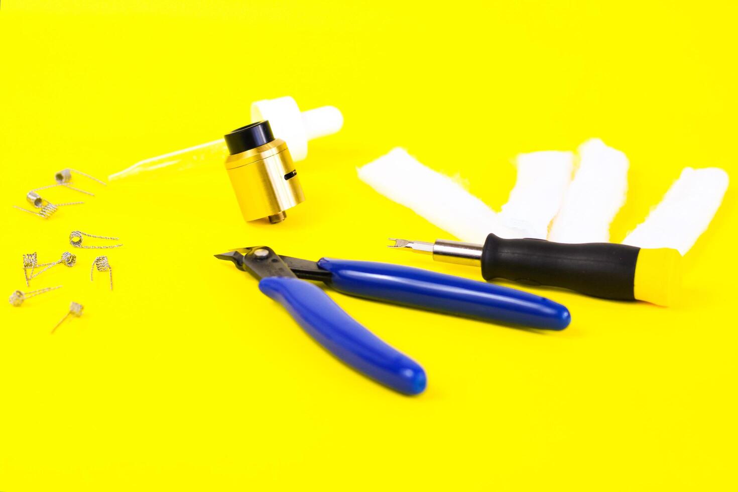 electronic cigarette details, Vata, coils, drip, spring, nippers on a yellow background. flat lay vape photo