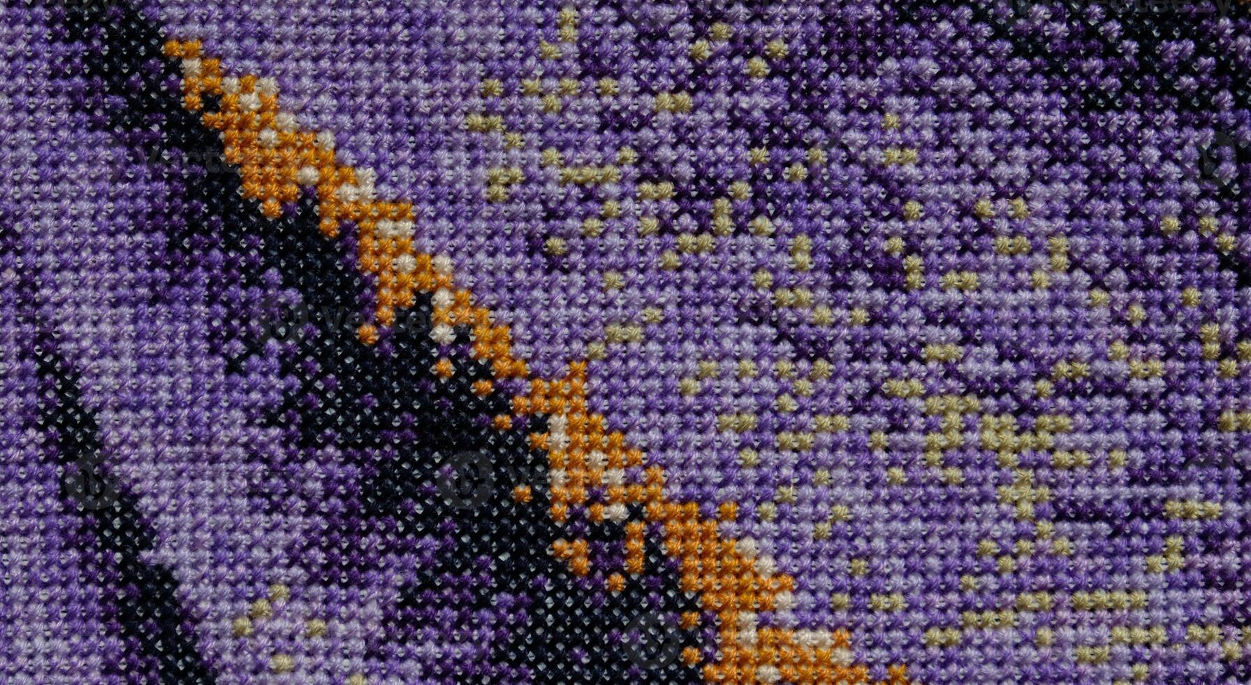 Purple, violet and brown close-up cross stitch background. Abstract Embroidered handmade Pattern. Needlework and DIY concept. Top view, macro, flat lay, mockup. photo