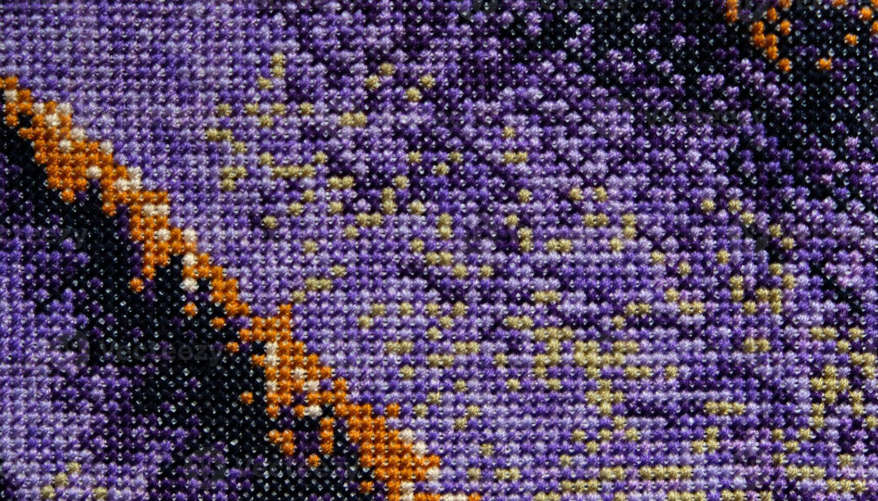 Purple, violet and brown close-up cross stitch background. Abstract Embroidered handmade Pattern. Needlework and DIY concept. Top view, macro, flat lay, mockup. photo