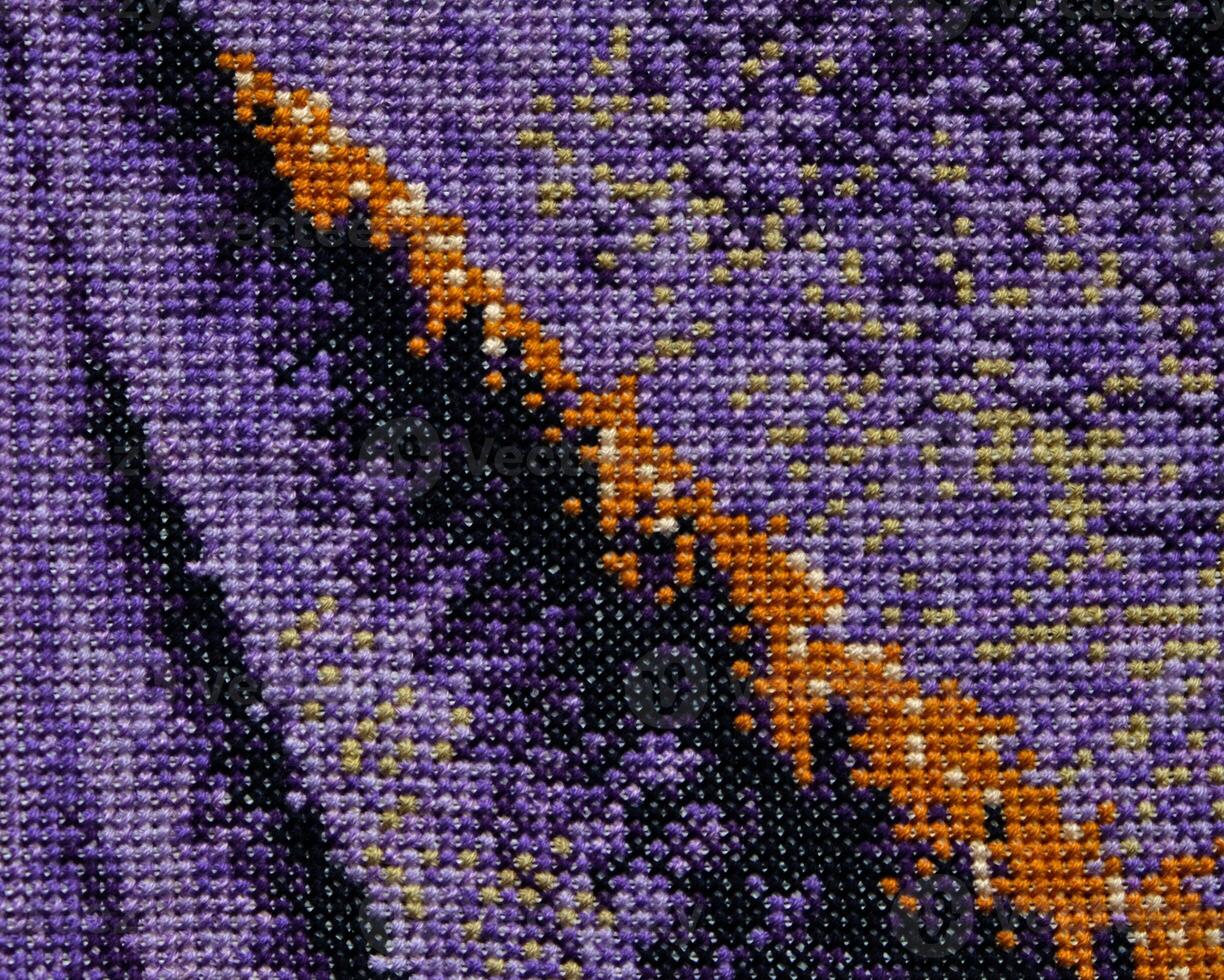 Purple, violet and brown close-up cross stitch background. Abstract Embroidered handmade Pattern. Needlework and DIY concept. Top view, macro, flat lay, mockup. photo