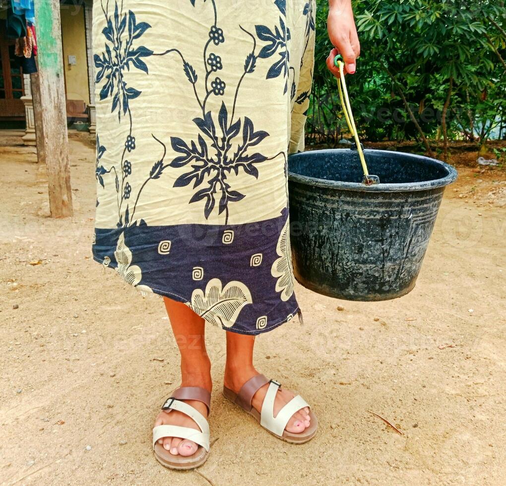 portrait of a woman in the interior of a village about to fetch water using a bucket photo