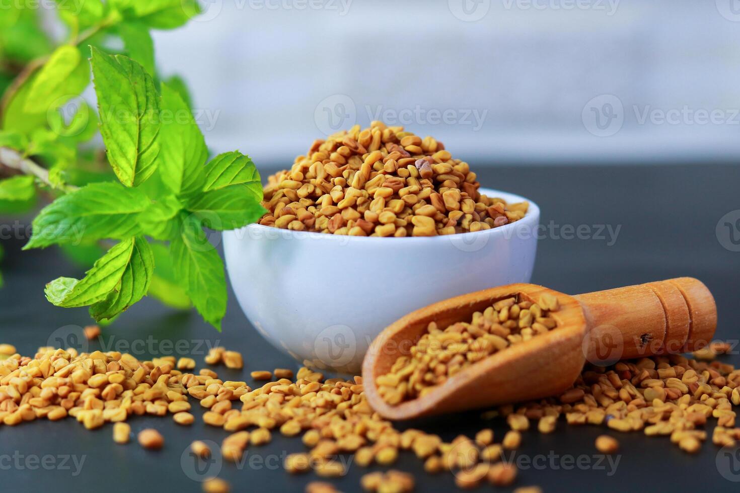Fenugreek seeds in a bowl on a blue background with green leaves photo