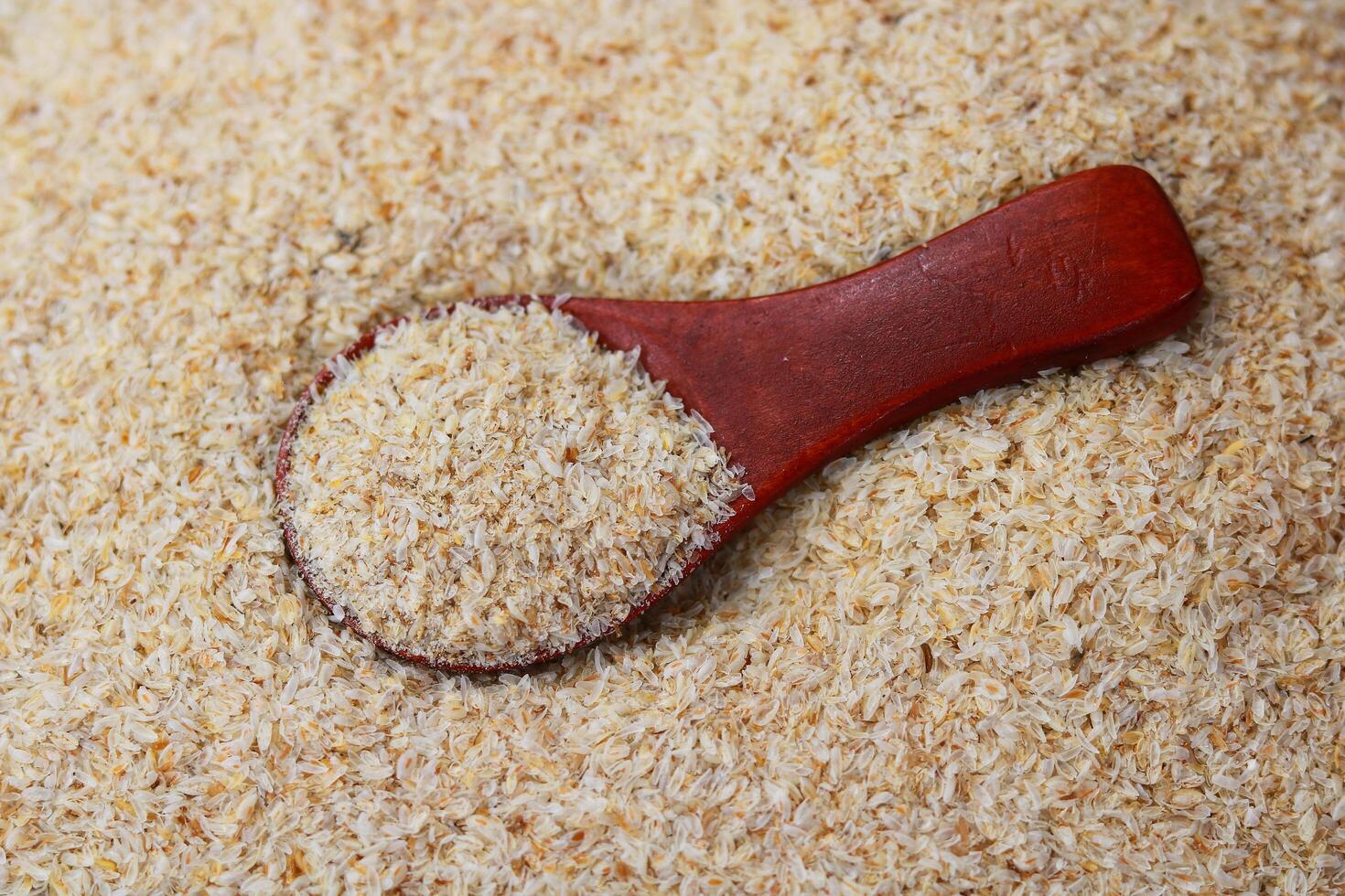 Psyllium Husk Isabgol in a wooden spoon on a background of Psyllium Husk photo