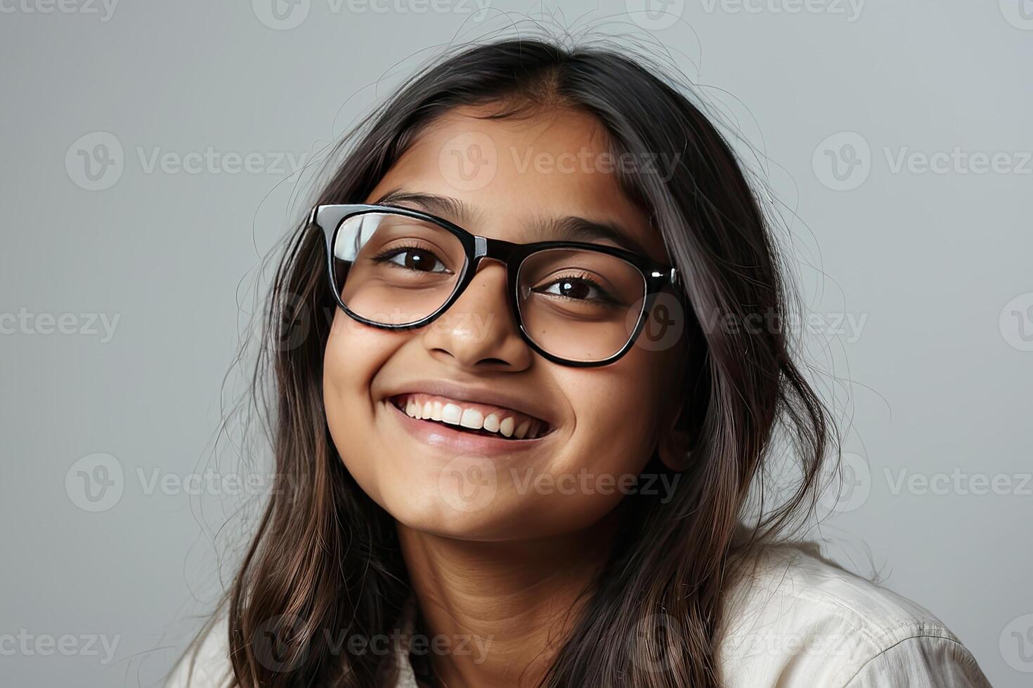 Portrait of a happy Indian schoolgirl teenager with glasses on a solid gray background. Back to school, correction of pupil kid eyesight. photo