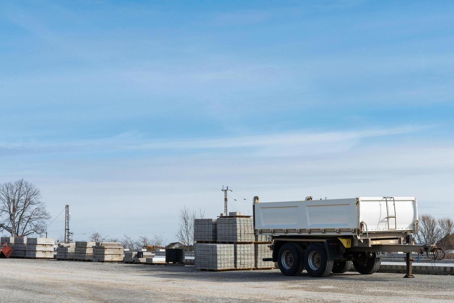 Construction site with empty car trailer and building materials stacked on pallets. photo