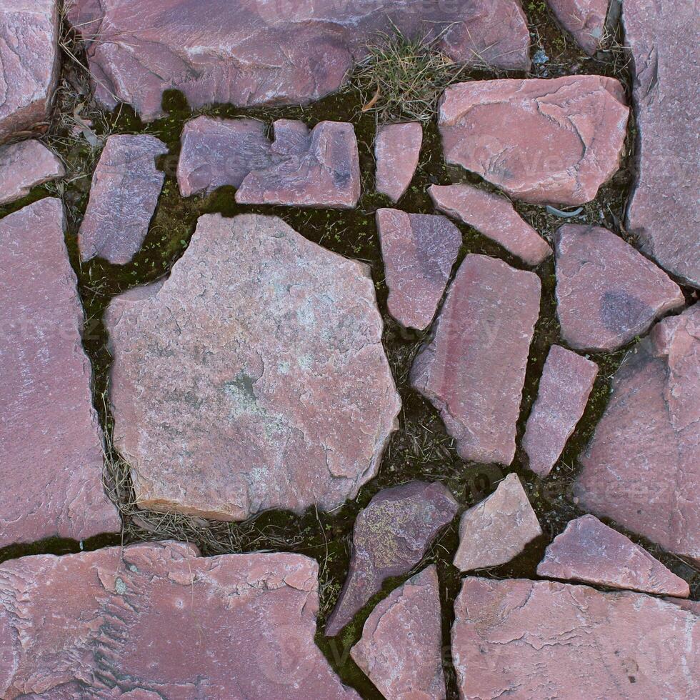Red granite stones placed in an old masonry texture background. Square stone background stock photo