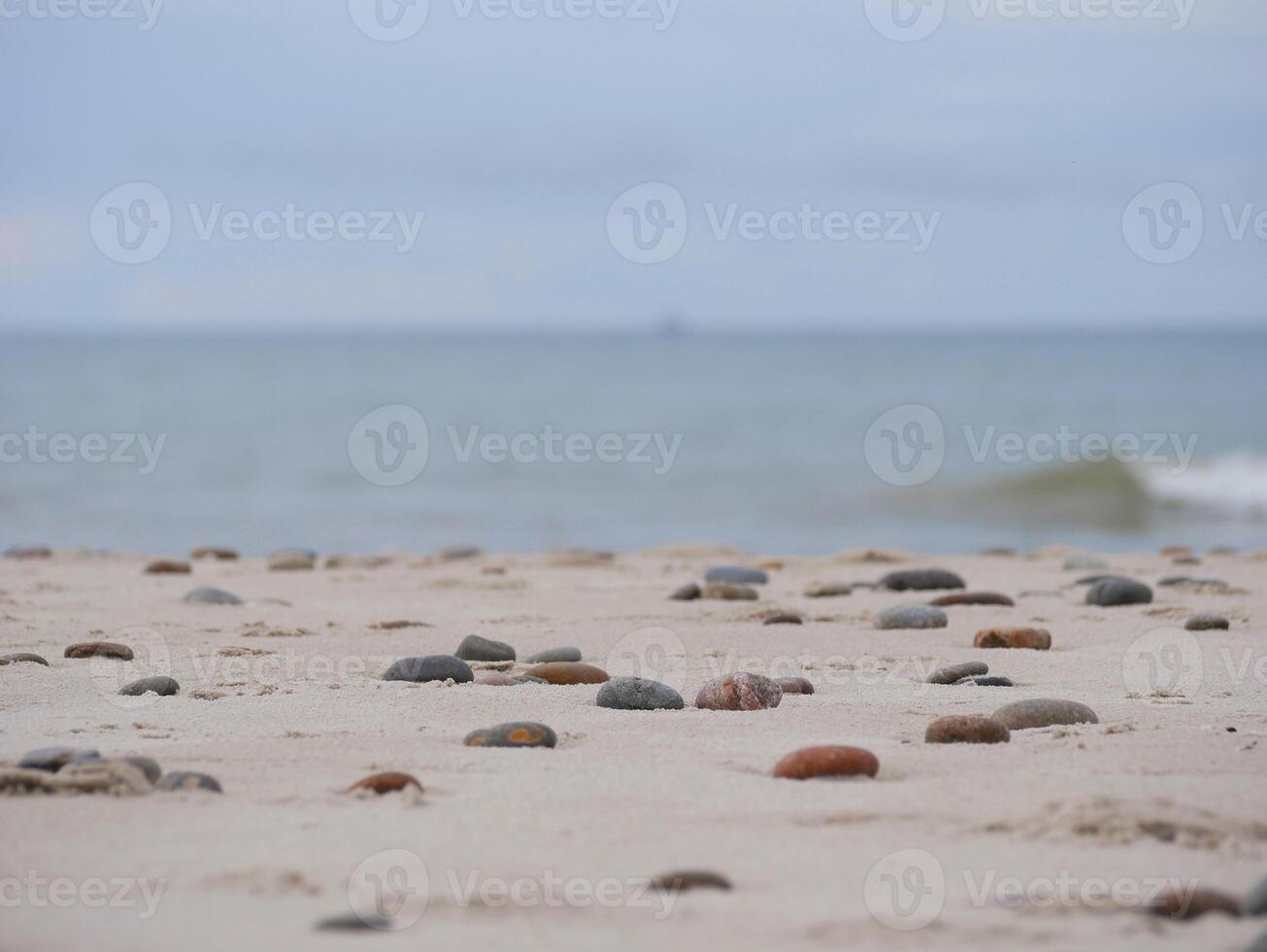 Seascape under a cloudy sky. Skagerrak, Kattegat strait in Skagen, Denmark. Stones on the sand at the foreground photo