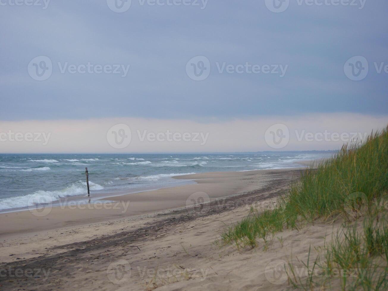Scenic view of the sea and sand dune on the beach on a gloomy, cloudy weather, Skagen, Denmark photo