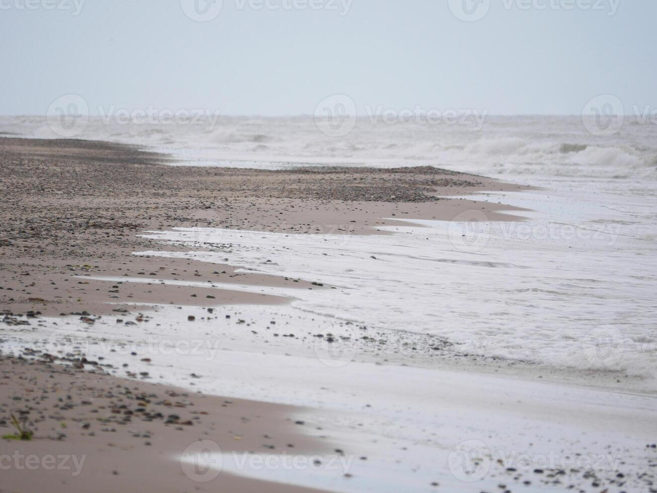 Seascape under a cloudy sky. Skagerrak, Kattegat strait in Skagen, Denmark. A lot of small stones on the sand photo