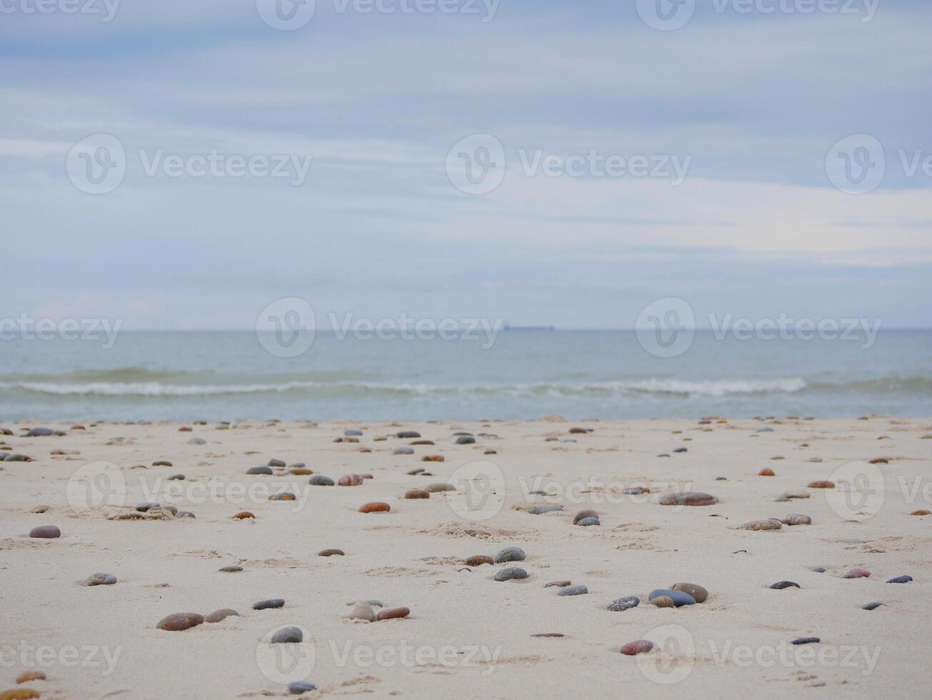Seascape under a cloudy sky. Skagerrak, Kattegat strait in Skagen, Denmark. Stones on the sand at the foreground photo