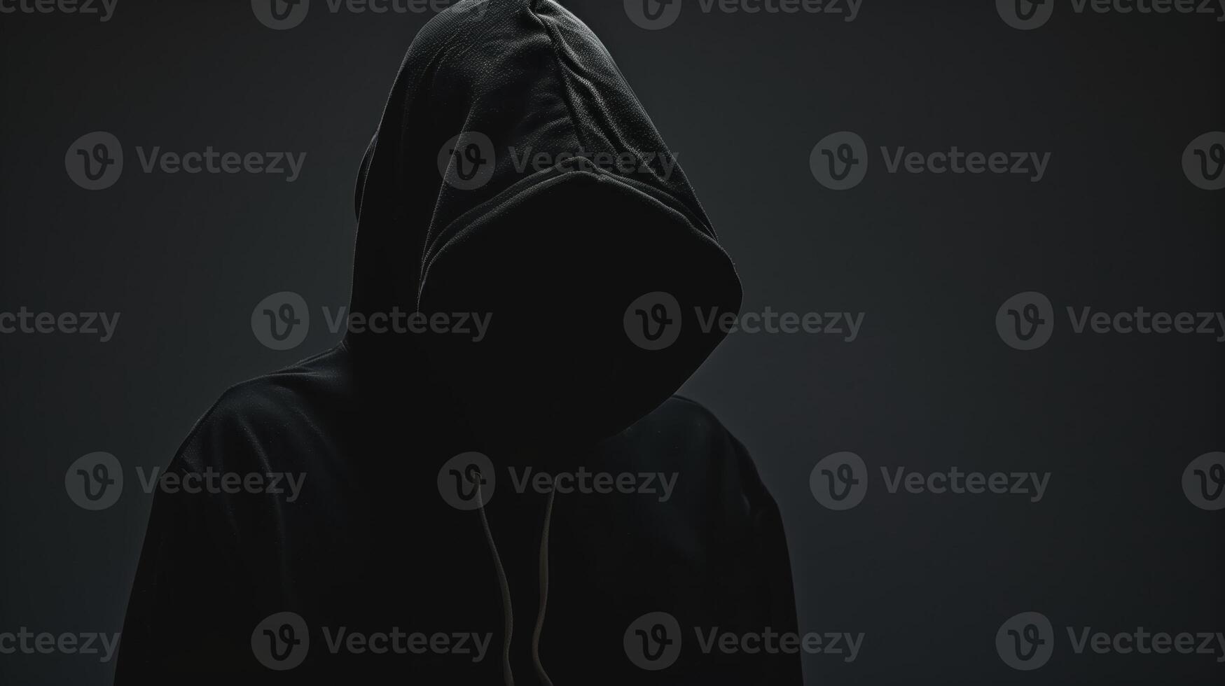 Anonymous Man in Black Hoodie with Hooded Face Evoking Mystery and Intrigue in Dark Setting photo