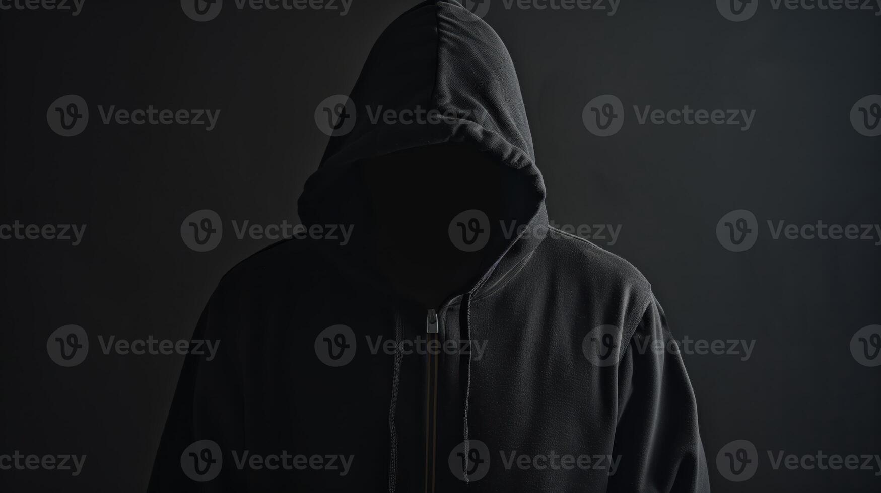 Anonymous Man in Black Hoodie with Hidden Face Against Dark Background for Mystery and Secrecy Themes photo