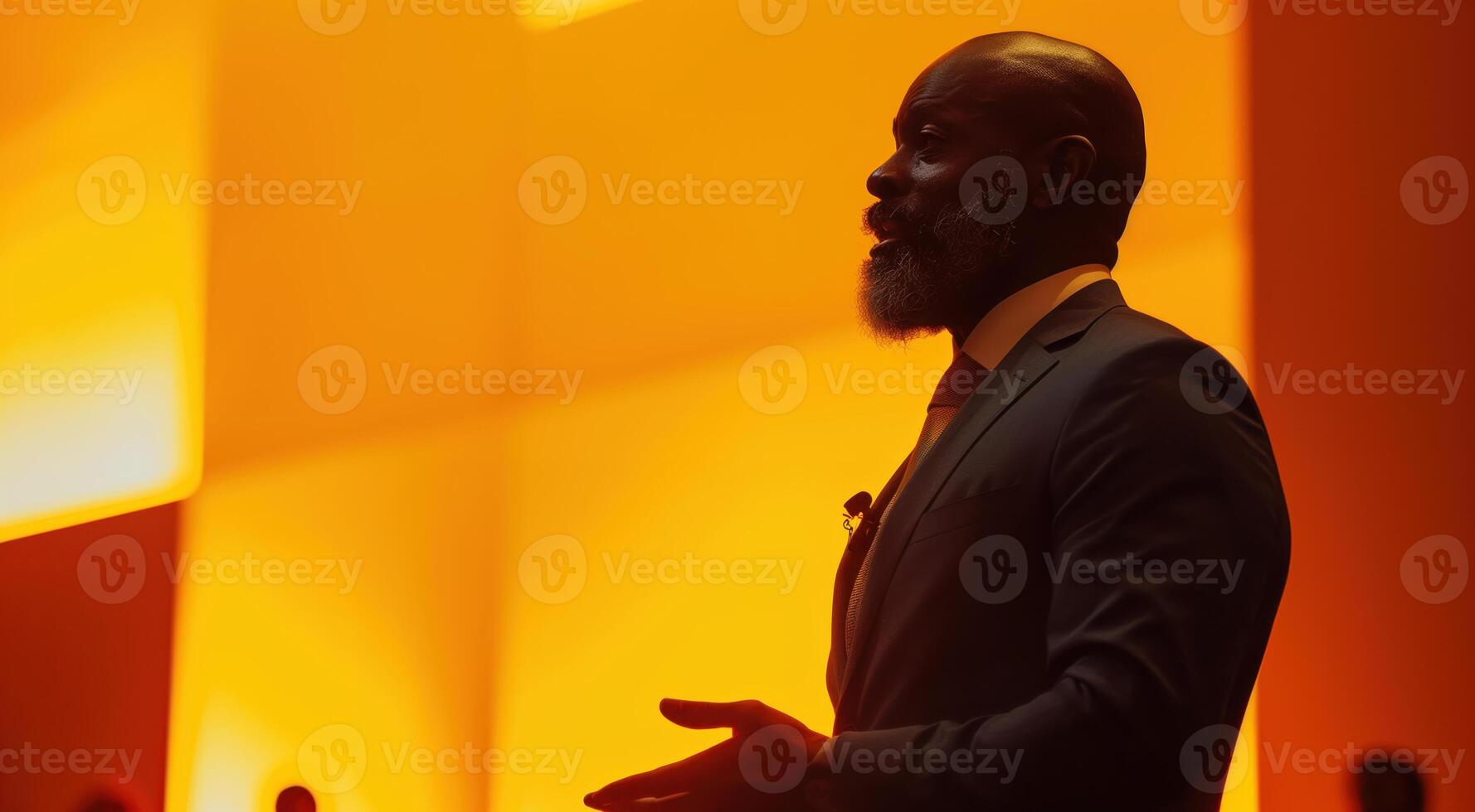 Dynamic Inspirational Speaker Delivering an Engaging Presentation in a Bright Orange Auditorium Setting photo