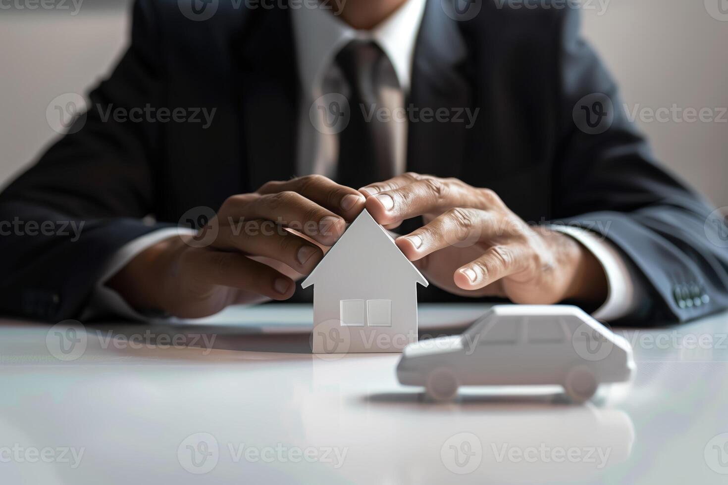 Professional Businessman in Suit Protecting Model House and Car Representing Insurance and Security photo