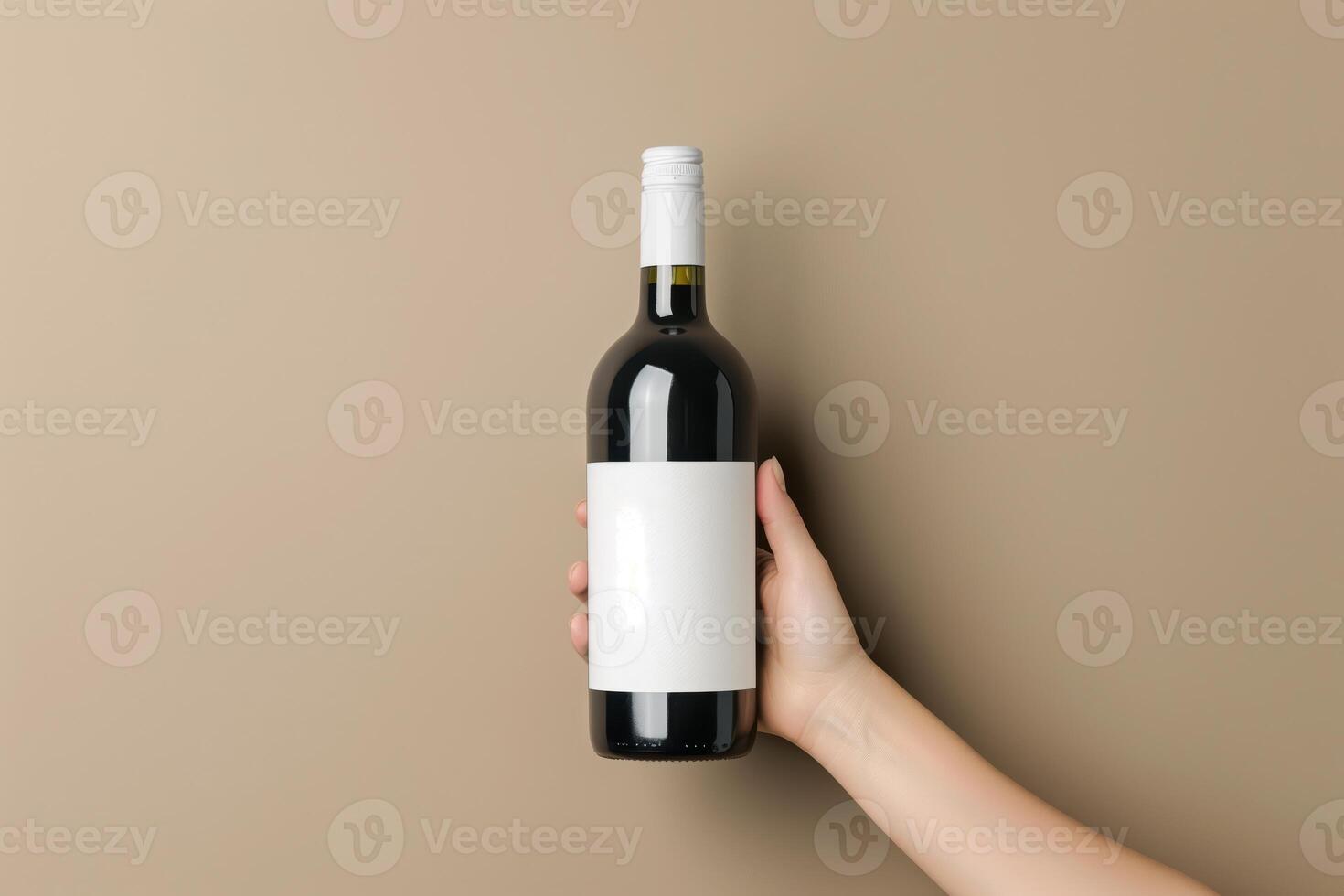 Woman's Hand Holding a Bottle of Wine Against a Neutral Light Brown Background photo