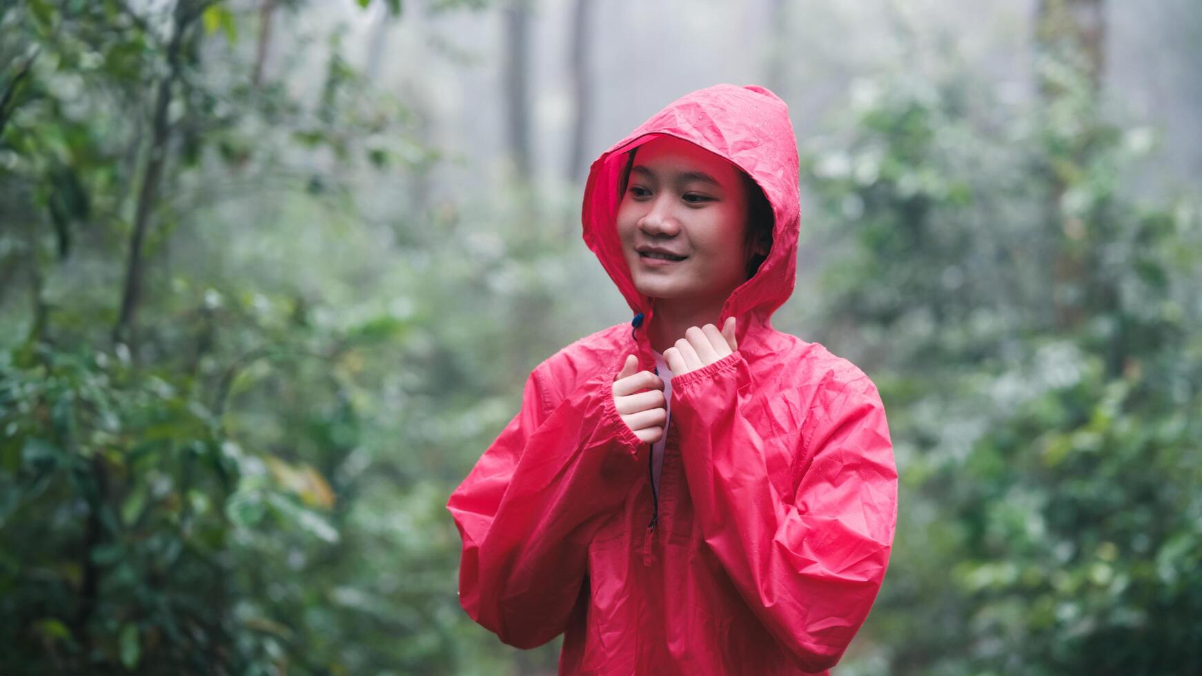 Smiling woman in red raincoat enjoying the forest photo