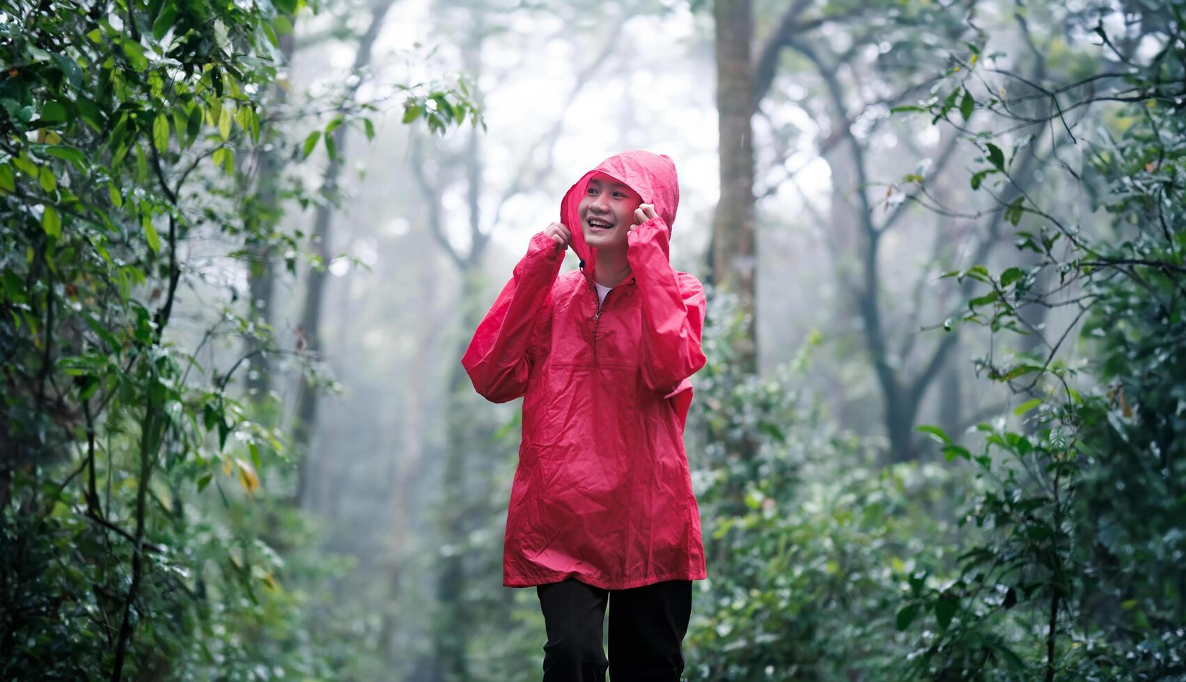 Smiling woman hiking through lush, misty forest on a rainy day photo