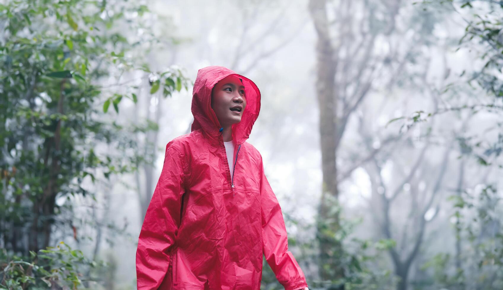 Smiling woman hiking through lush, misty forest on a rainy day photo