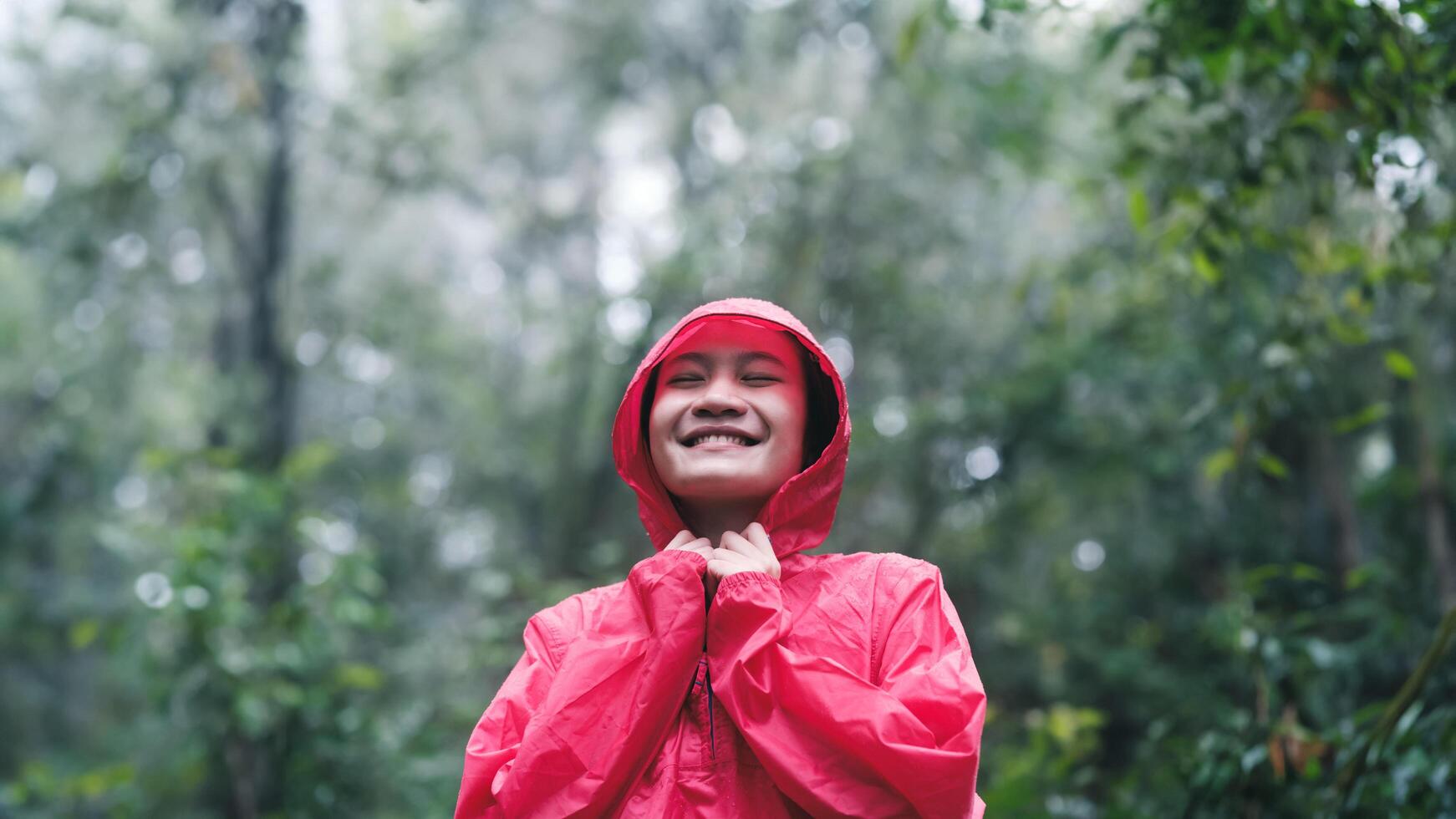 Smiling woman in red raincoat enjoying the forest photo