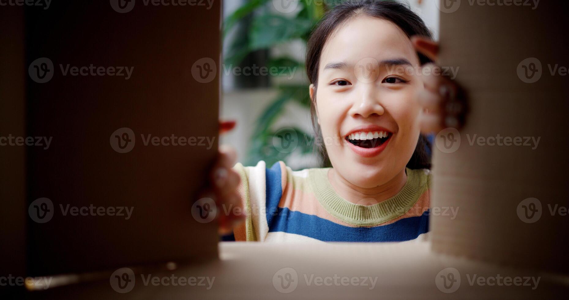 Selective focus, Happy young woman open a cardboard box to look at the items she moved from old home. Moving house and lifestyle concept. photo