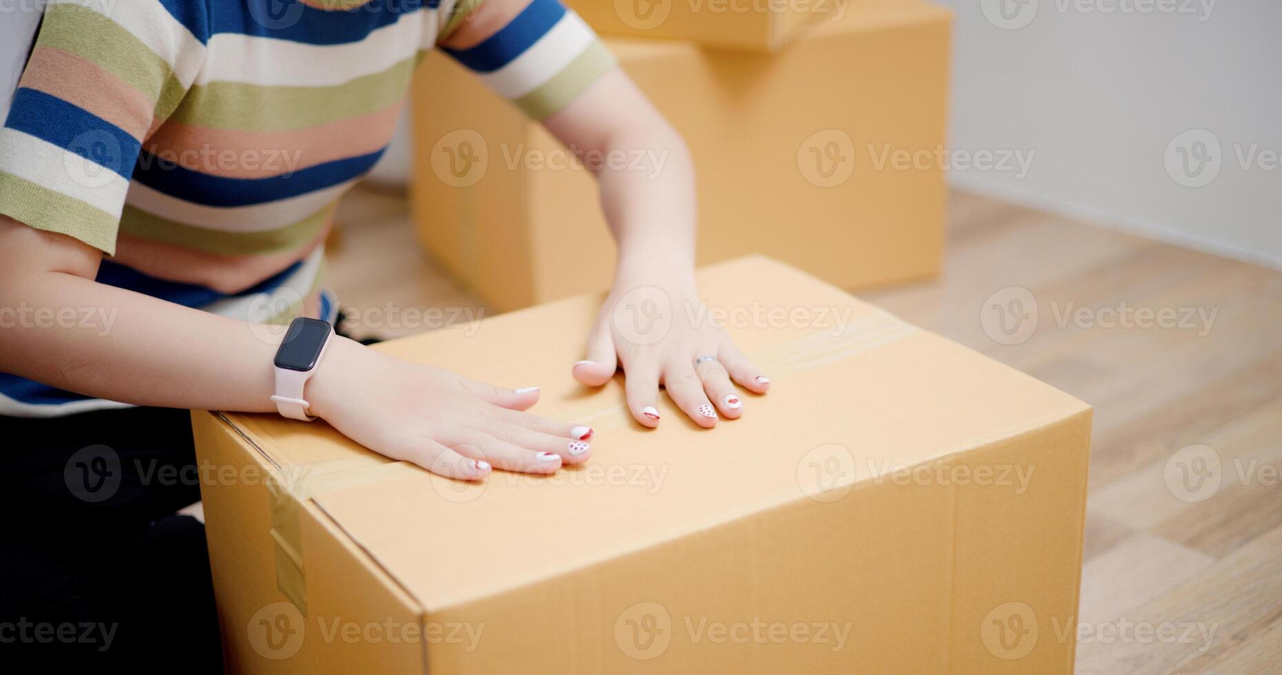 Selective focus, Hands of Young Asian woman wrapping cardboard boxes with duct tape in preparation for moving into new house. Moving house and lifestyle concept. photo