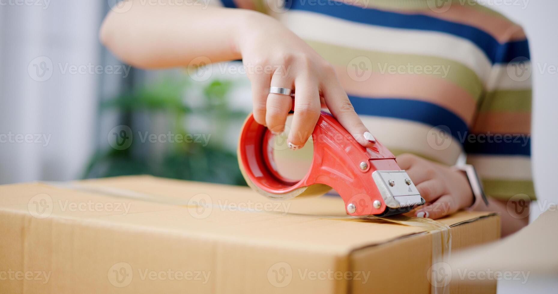 Selective focus, Hands of Young Asian woman wrapping cardboard boxes with duct tape in preparation for moving into new house. Moving house and lifestyle concept. photo