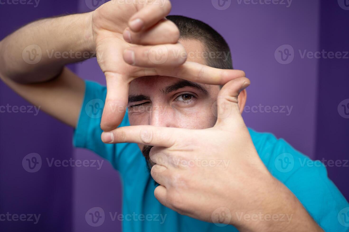 Young handsome man doing frame using hands palms and fingers, over purple background photo