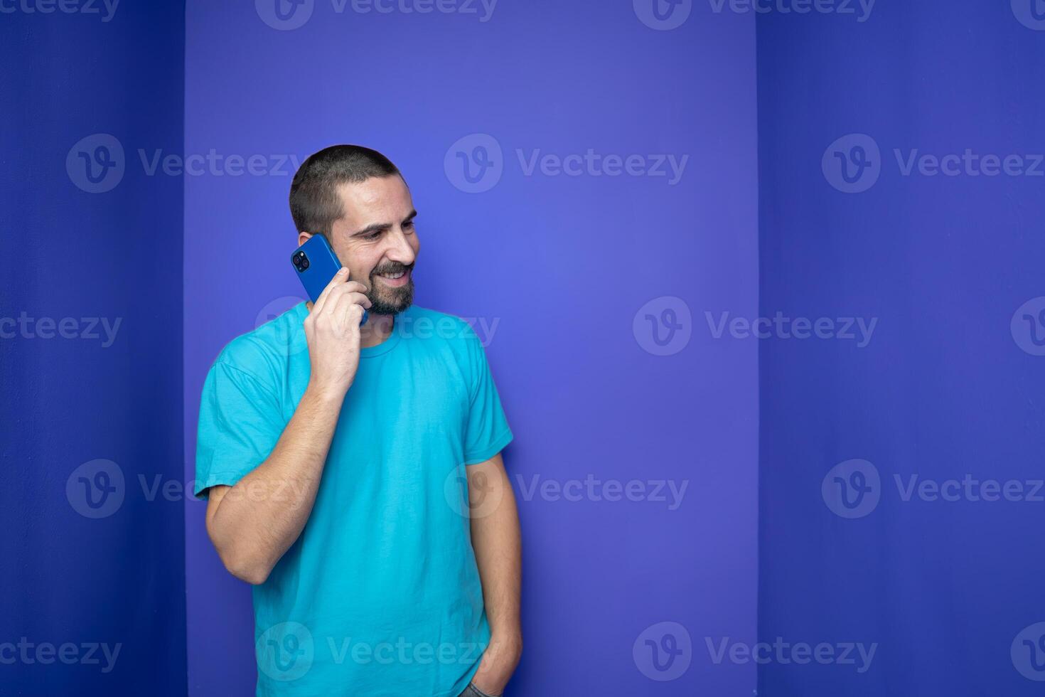 Happy young man talking with mobile phone on color background photo