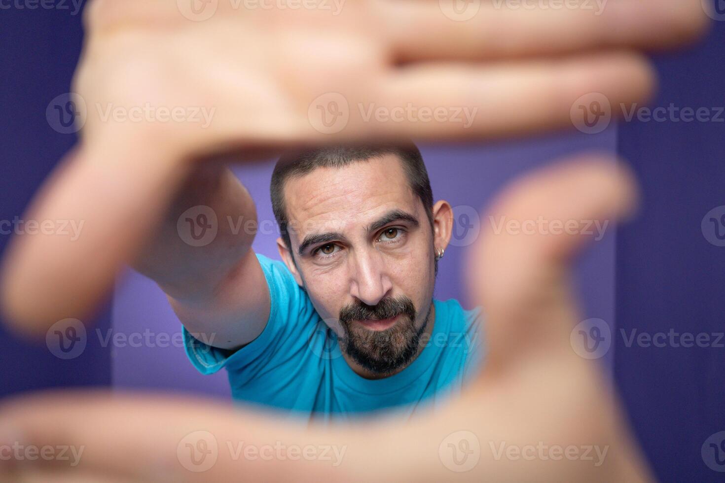 Young man doing frame using hands and fingers, isolated over purple background photo