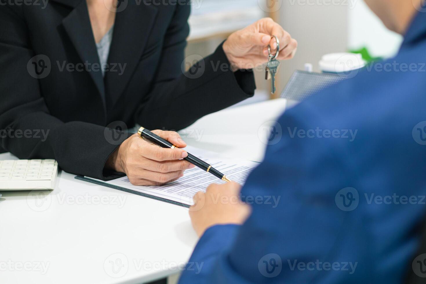 Real estate agent handing over house keys to customer after agreeing to sign sales contract and signing real estate handover contract to customer. Successful real estate sales contract concept photo