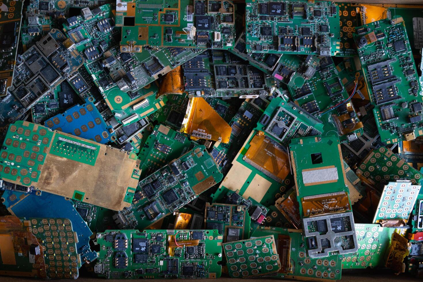 pile of electronic waste on factory floor is circuit board of mobile phone waiting to be processed extract gold to separate precious metal from electronic waste. extracting precious metal from e-waste photo