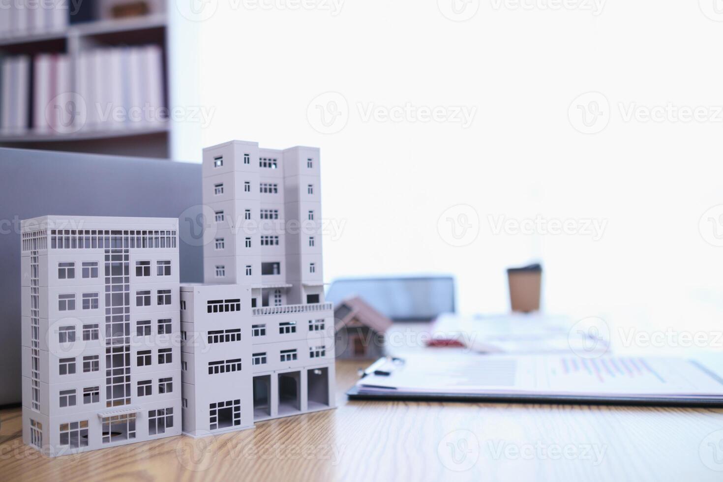 Mock up of building and documents placed on the desk of the agent in the real estate office to prepare for the customers who will come to see the property before deciding to buy the real estate. photo