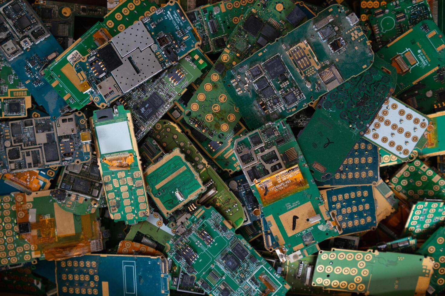pile of electronic waste on factory floor is circuit board of mobile phone waiting to be processed extract gold to separate precious metal from electronic waste. extracting precious metal from e-waste photo